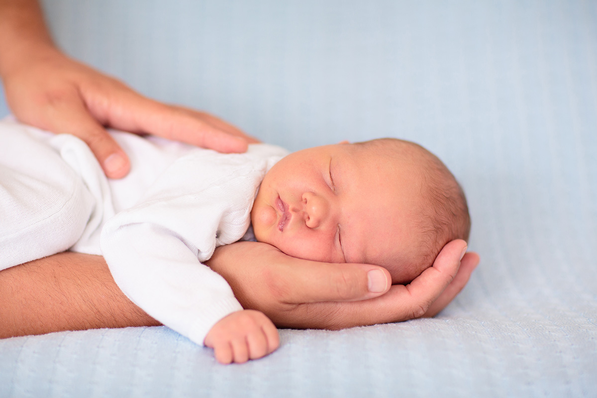 Bebelus nou nascut de sex masculin intins in pat, ilustrand primele momente de viata si ingrijirea noului nascut