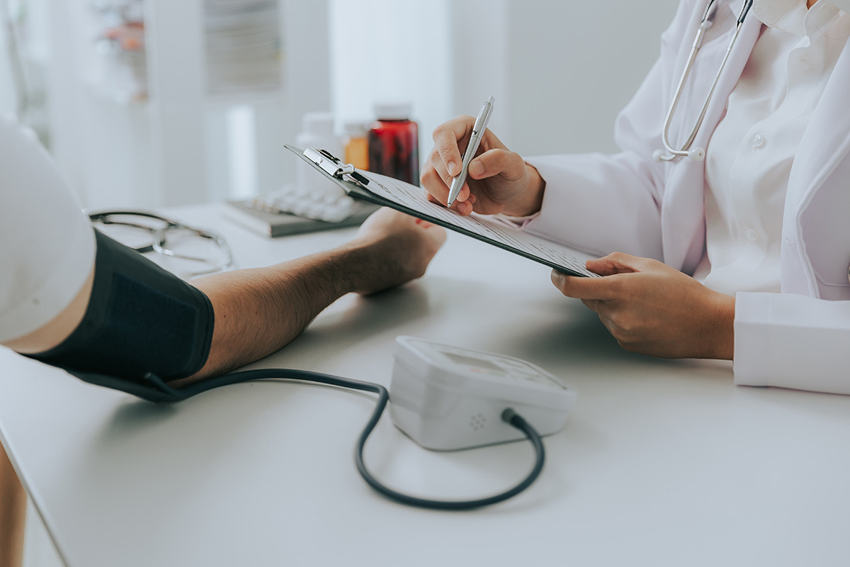 Medic examinand pacient cu hipertensiune in cabinet.