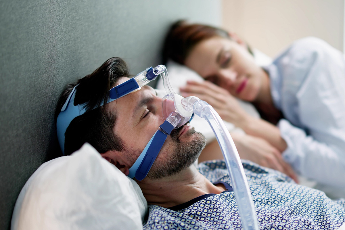 Barbat purtand aparat CPAP pentru apnee in somn