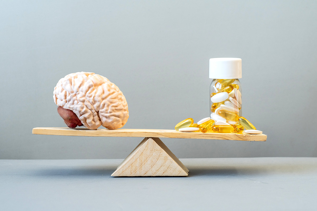 Model al creierului uman si suplimente pentru sustinerea functiei cerebrale asezate pe un cantar de echilibru, ilustrand conceptul de echilibru intre nutritie si sanatatea creierului.