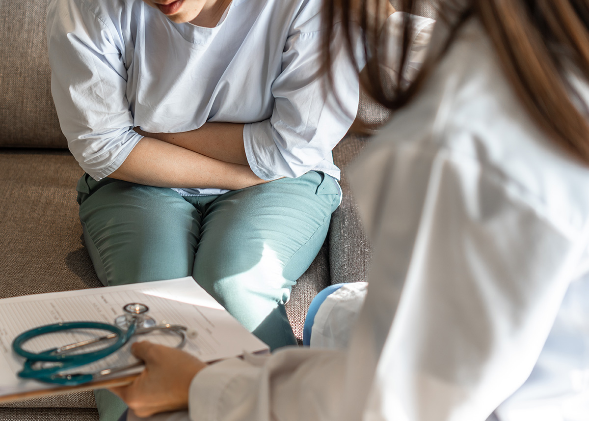 Pacienta cu dureri abdominale cauzate de sindromul de colon iritabil vorbind cu un medic.