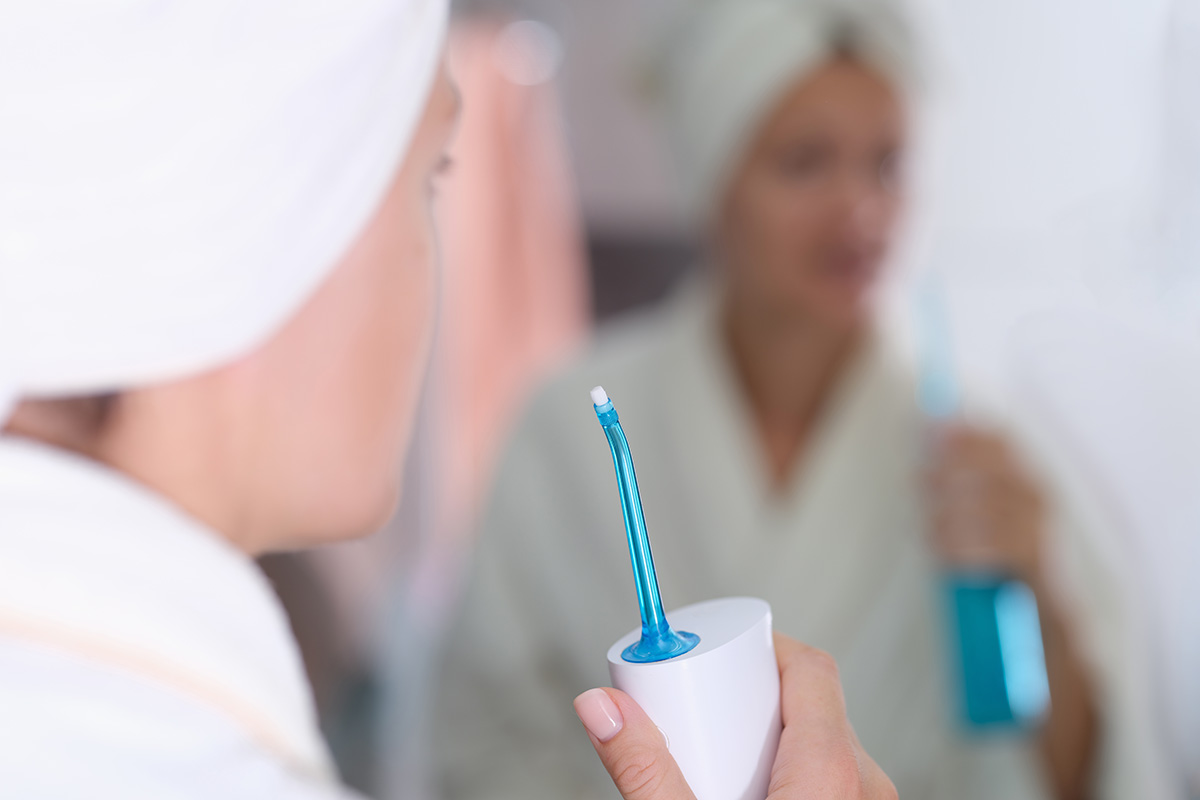 Femeie pregatindu-se sa folosesca un dus bucal dupa baie