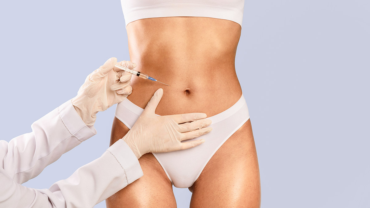 Abdomenul unei femei si mainile unui medic pregatit sa aplica o injectie