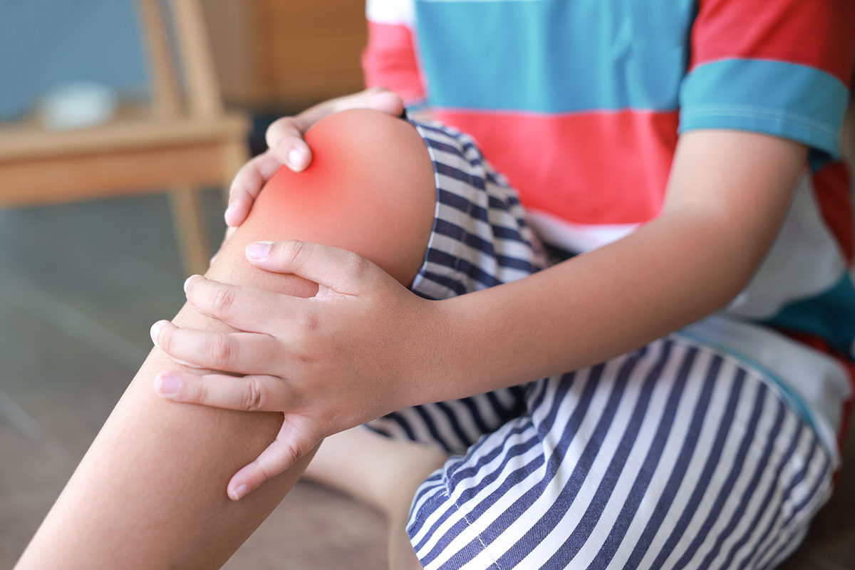 Baietel isi tine genunchiul inflamat din cauza durerii dupa o accidentare