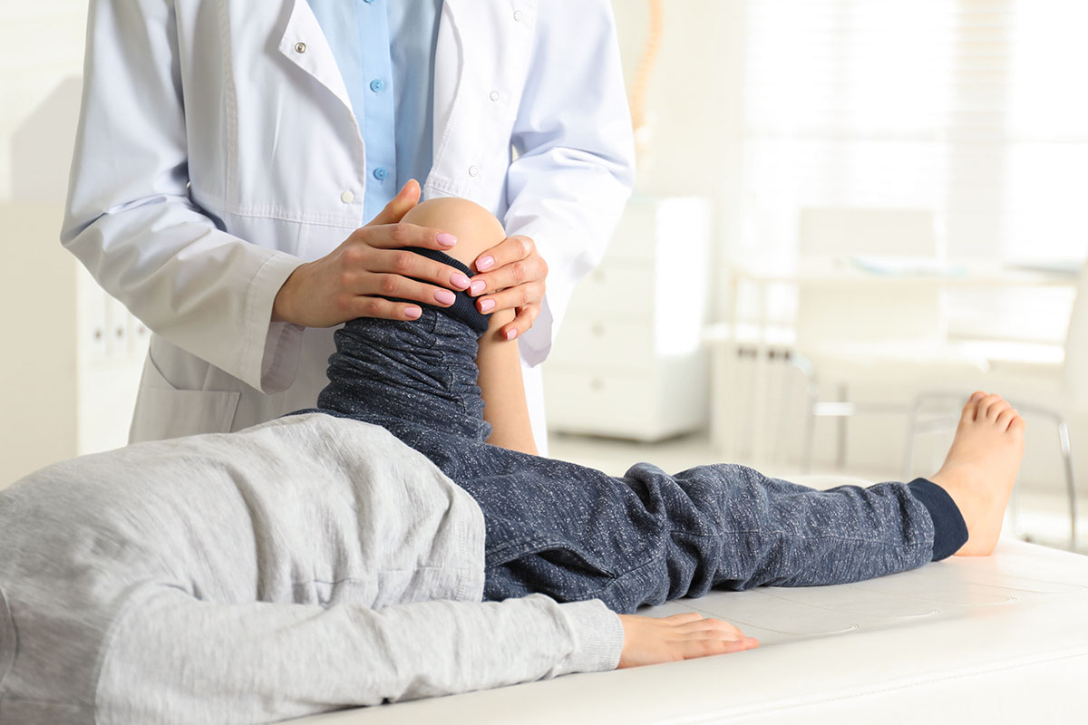 Medic ortoped care examineaza piciorul unui copil