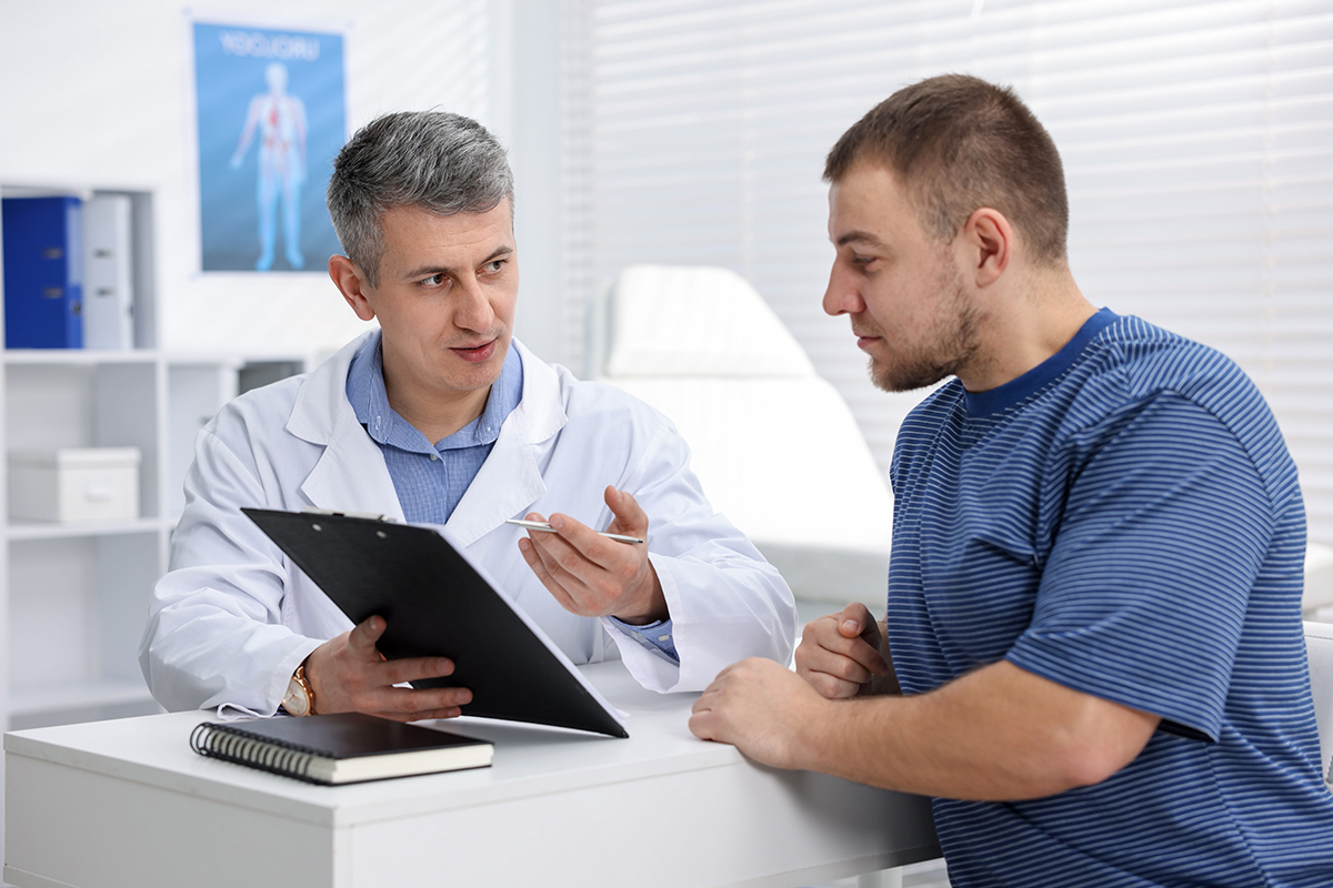 Urolog explica pacientului rezultatele consultului folosind o planseta medicala