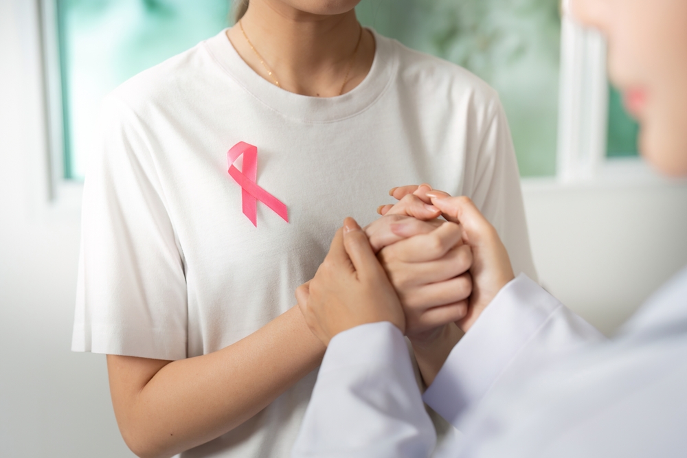 Doua femei se tin de mana oferind sprijin in lupta impotriva cancerului mamar