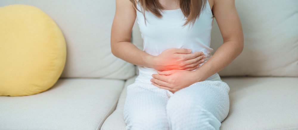 Femeie resimte dureri abdominale si isi tine stomacul din cauza disconfortului