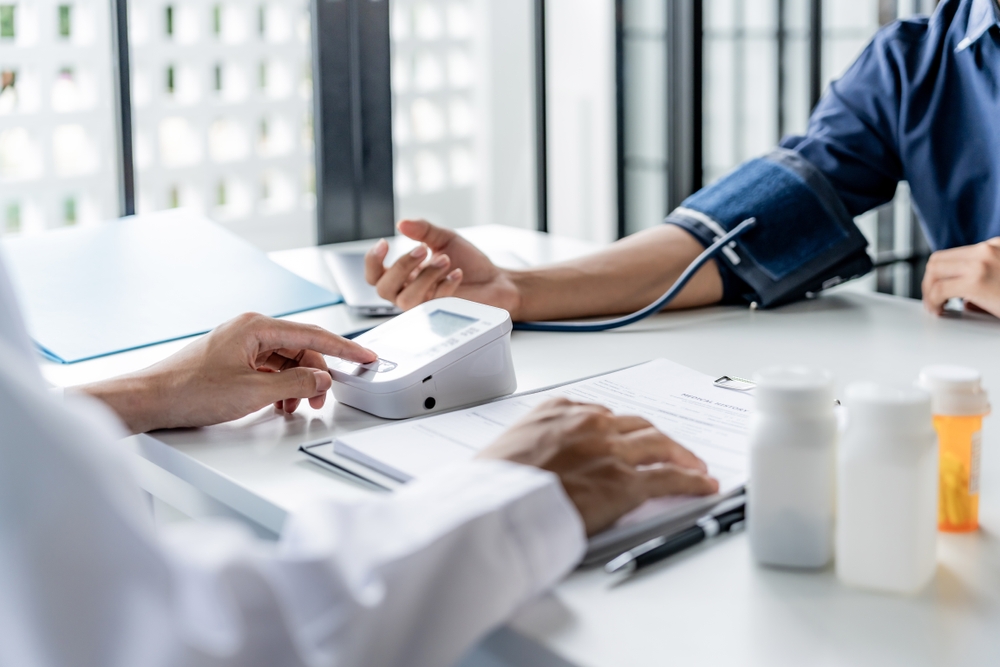 Medic masoara tensiunea arteriala pacientului in timpul unei consultatii medicale
