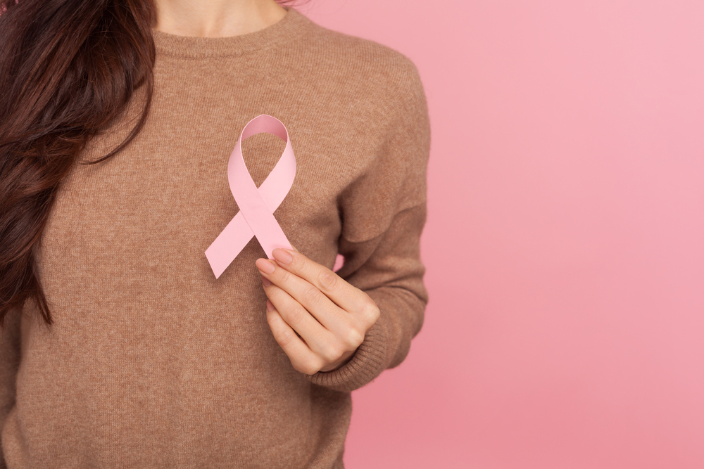 femeie in pulover maro cu fundita cancerului de san