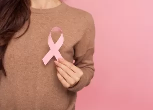 Femeie care care tine in mana o panglica roz, ca simbol al cancerului la san