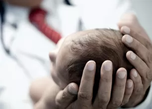 Pediatru tinand in maini un nou-nascut