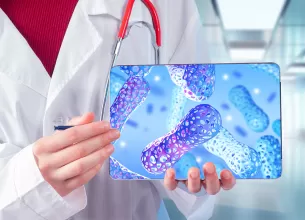 Doctor recomandand probiotice, aratand spre o tableta cu o ilustratie a celulelor microbiotei intestinale colorate