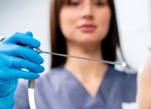 Medic ORL efectueaza o endoscopie nazala unui pacient in cabinetul medical