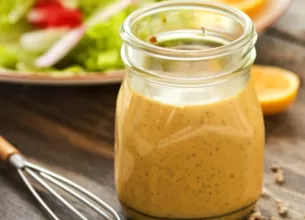 Borcan cu mustar langa un bol de salata