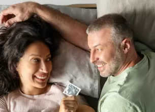 Cuplu, in pat, ea tine un prezervativ