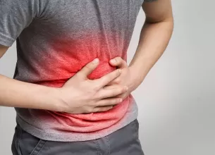 Barbat bolnav care se tine de burta, suferind de durere abdominala intensa
