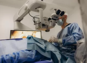 Chirurg care priveste prin microscop in sala de operatie in timpul unei operatii de cataracta