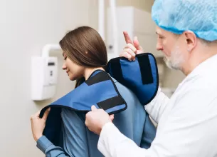 Medic echipeaza pacienta cu protectie radiatii