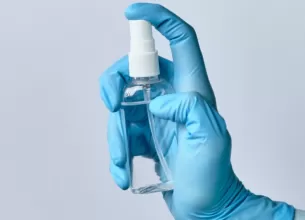 Medic in halat si manusi medicale, tinand un spray dezinfectant, pregatit pentru procedura