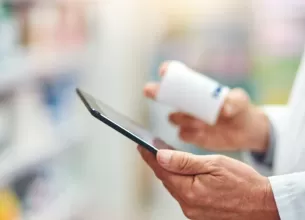 Personal medical verificand eticheta unui recipient cu medicamente intr-o farmacie