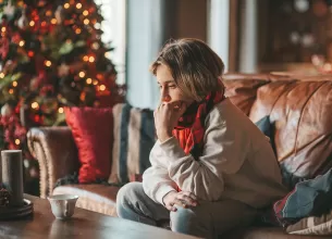 Tanara ingrijorata si trista langa bradul de Craciun