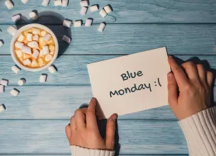 Mainile unei femei care tin un bilet cu scrisul Blue Monday