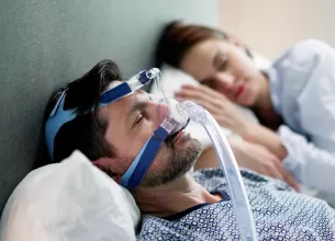 Barbat purtand aparat CPAP pentru apnee in somn