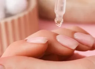 Femeie aplicand ulei de cuticule la unghiile de la maini