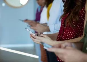 Grup de prieteni utilizand telefoanele in timp ce asteapta sa inceapa o sedinta