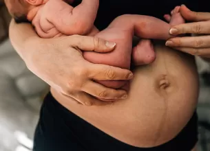 Mama in perioada de lehuzie tinandu-si bebelusul in brate