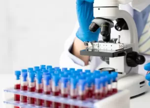 Mana unui medic preluand o eprubeta cu proba de sange pentru analize de laborator, evidentiind procedura medicala de diagnostic si investigatie clinica