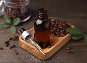 Sticluta cu ulei de esential de cuisoare, langa muguri uscati de cuisoare.