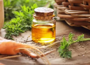 Sticluta cu ulei de morcov, langa morcovi proaspeti