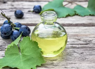 Sticluta cu ulei de struguri langa boabe de struguri negri