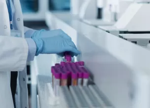 Tehnician de laborator in halat alb analizeaza probe de sange in mediu medical steril