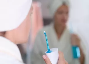 Femeie pregatindu-se sa folosesca un dus bucal dupa baie