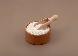 Granule de sorbat de potasiu pe o lingura de lemn, ilustrand utilizarea conservantului alimentar in preventia dezvoltarii microorganismelor.