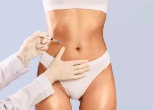 Abdomenul unei femei si mainile unui medic pregatit sa aplica o injectie