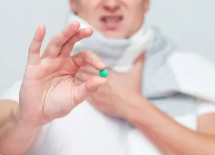Barbat tine intre degete o pastila verde pregatita pentru administrare