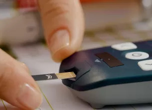 Femeie introduce cu atentie banda de test intr-un aparat pentru glicemie