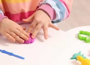 Mainile unei fetite ce se joaca cu plastilina