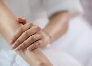 Femeie acoperindu-si bratul cu mana opusa.