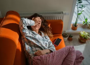 Femeie epuizata si lipsita de energie sta intinsa in pat acasa