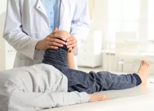 Medic ortoped care examineaza piciorul unui copil