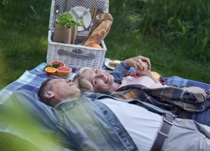 Cuplu matur relaxat sta intins pe iarba si se bucura de un stil de viata sanatos