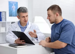Urolog explica pacientului rezultatele consultului folosind o planseta medicala