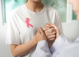 Doua femei se tin de mana oferind sprijin in lupta impotriva cancerului mamar
