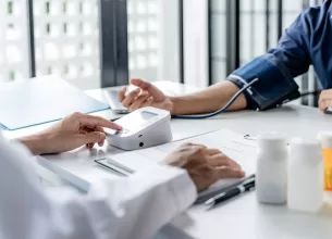 Medic masoara tensiunea arteriala pacientului in timpul unei consultatii medicale