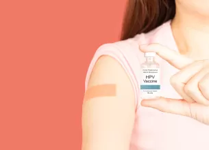 O femeie care tine in mana un flacon cu vaccin impotriva HPV